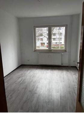 3. Zimmer mit Blick zum Fenster. Helle Wände und hellgrauer Bodenbelag in Holzoptik.JPG - 
