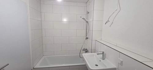 Weiß gefliestes Bad mit Badewanne. - 
