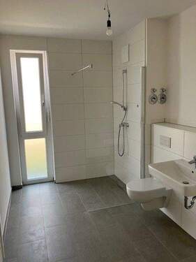 Bad mit Fenster, bodengleicher Dusche, weißen Sanitärobjekten, weiißen Wandfliesen, dunkelgrauen Bodenfliesen und Waschmaschinenanschluss - Etagenwohnung mit 90,80 m&sup2; in Heppenheim zur Miete