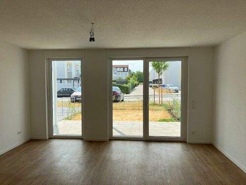 Wohnzimmer mit Blick auf die Terrasse und kleinem Garten. Weiße Wände, brauner Vinyl-Designboden in Holzoptik - 