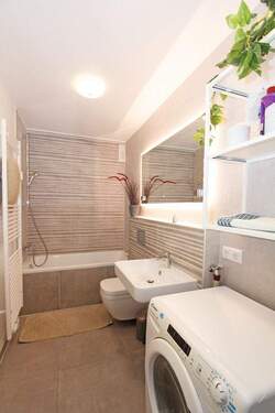 Badezimmer mit Badewanne, Dusche, WC sowie Waschmaschine - 