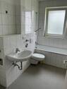 Bad mit Fenster, weißen Sanitärobjekten, weißen Wandfliesen und grauen Bodenfliesen - Etagenwohnung mit 70,90 m&sup2; in Bad Vilbel zur Miete