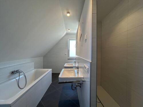 Badezimmer mit großer bodentiefer Dusche, Badewanne, WC und zwei Waschbecken - 