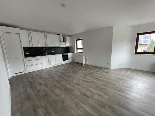 Eine moderne Einbauküche ist im Wohn- Essbereich integriert. - 