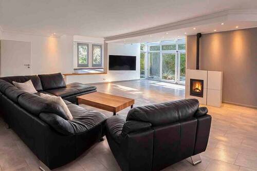 Offener Wohnbereich mit Kamin und großer Fensterfront - 