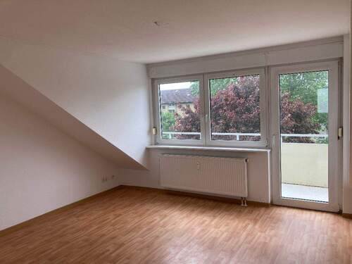 Wohnzimmer mit Dachschrägen, weißen Wänden, Bodenbelag in Holzoptik und Zugang zum Balkon - 2 Zimmer Etagenwohnung in Bad Vilbel