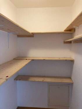 Abstellraum mit hellen Wänden und mehreren Holzregalen - 