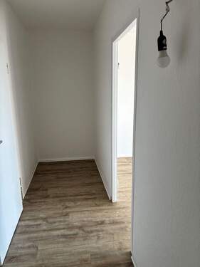 Flur mit Blick Richtung Abstellbereich, weiß angelegte Wände und brauner Vinyl-Designboden in Holzoptik - Etagenwohnung mit 44,10 m&sup2; in Darmstadt zur Miete