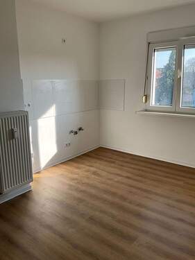 Küche mit Fenster, braunem Boden und weißen Wand- und Deckenflächen..JPG - 