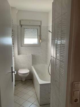 Badezimmer mit Fenster und Badewanne. Helle Fliesen an den Wänden und Boden..JPG - 