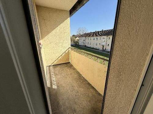 Blick von Wohnzimmer auf Balkon mit grauem Betonboden und Blick auf Rasen der Außenanlage - 3 Zimmer Etagenwohnung in Meerbusch