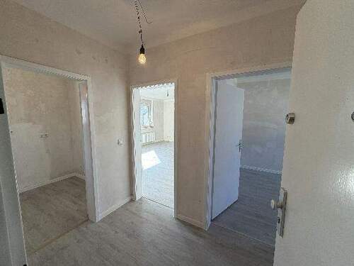 Blick von Wohnungseingangstür in Diele mit grauem PVC-Boden und tapezierfähigen Wänden von dort sieht man die Zimmereingänge mit weißen Türrahmen - Etagenwohnung mit 63,10 m&sup2; in Meerbusch zur Miete