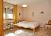 Helles Schlafzimmer mit Fensterfront und klassischer Heizanlage - 