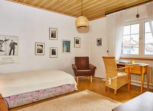 Helles Schlafzimmer mit Holzdecke und großzügigen Fensterflächenüber die gesamte Wandseite - 