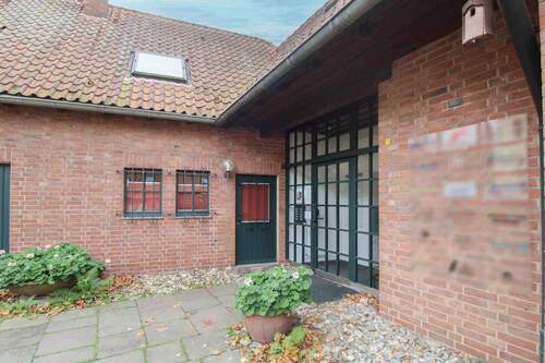 Stilvoller Eingangsbereich mit traditioneller Klinkerarchitektur und begrüntem Vorplatz - 