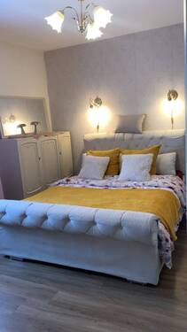 Schlafzimmer_Doppelbett_weißes Schränkchen_Mustertapete.jpg - 