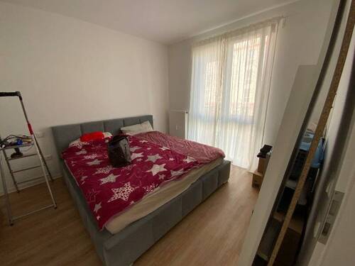 Schlafzimmer mit hellem Holzfußboden, bodentiefen Fenstern und weiß gestrichenen Wänden.JPG - 