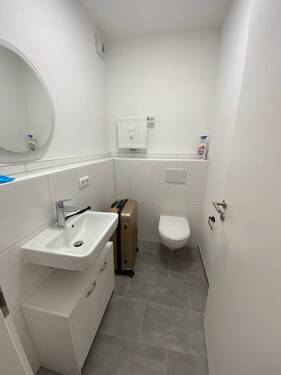Gäste-WC mit grauen Bodenfliesen und weißen Wandfliesen, WC und Waschbecken.JPG - 
