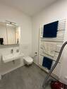 Badezimmer mit grauen Bodenfliesen und weißen Wandfliesen, WC und Waschbecken.JPG - 