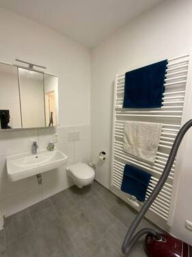 Badezimmer mit grauen Bodenfliesen und weißen Wandfliesen, WC und Waschbecken.JPG - 