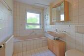 Helles Badezimmer mit Badewanne und Fenster - 