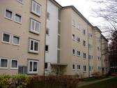 Vorderansicht eines mehrstöckigen Wohngebäudes mit Balkonen, umgeben von Bäumen und grünen Sträuchern - 3 Zimmer Etagenwohnung zur Miete in Kassel
