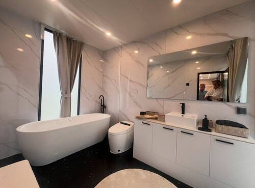 Wellness-Oase mit freistehender Badewanne und luxuriöser Marmor-Wandverkleidung - 