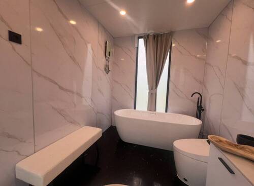 Luxus-Wellness-Oase: Freistehende Badewanne mit elegantem Marmor-Ambiente und natürlichem Lichteinfall - 