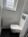 Tageslicht-WC mit weiß angelegten Wänden und weißem Fliesenspiegel - 