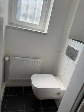 Tageslicht-WC mit weiß angelegten Wänden und weißem Fliesenspiegel - 
