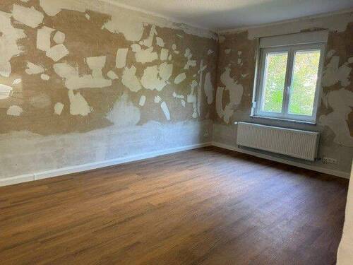 Wohnzimmer mit tapetenfreien Wänden und braunem Vinyl-Designboden in Holzoptik - 