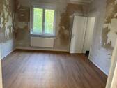 Schlafzimmer mit tapetenfreien Wänden, braunem Vinyl-Designboden in Holzoptik und Zugang zum Bad - 