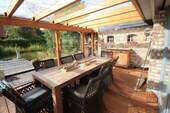 überdachter Terrassenbereich mit Blick auf Terrasse und Gartenteich - 