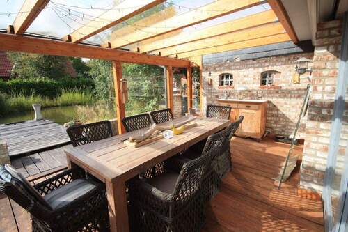 überdachter Terrassenbereich mit Blick auf Terrasse und Gartenteich - 