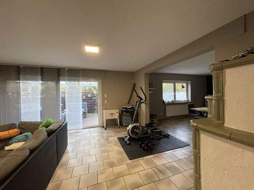 Wohnzimmer mit Kachelofen und Zugang zur Terrasse - 