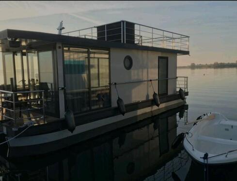 Foto - Festliegendes Hausboot mit großer Dachterrasse und Ruderboot