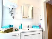 Modernes Badezimmer mit Spiegelschrank und großflächiger Keramikfliesen-Wandgestaltung - 
