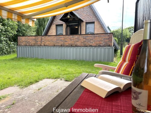 Terrassenbereich mit ausfahrbarem Sonnenschutz und Blick auf die Ziegelfassade - 