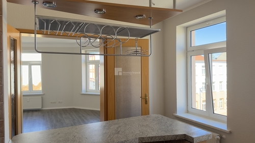 Einbauküche mit Tresen und Flügeltür zum Wohnzimmer - 