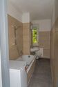 Badezimmer mit WC, Wanne, Waschmaschine und Fenster - 