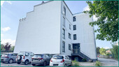 Ansicht der Gebäudeseite mit Hauszugang und Parkplätzen - 