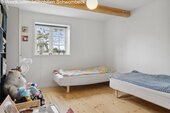 Helles Kinderzimmer mit großflächigem Fenster und Holzbalkendecke - 