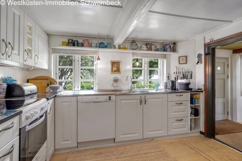 Helle Küche mit umlaufender Arbeitsfläche und großzügigen Fensterfronten zum Garten - 