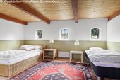 Komfortables Gästezimmer mit Holzbalkendecke und drei Rundbogenfenstern - 