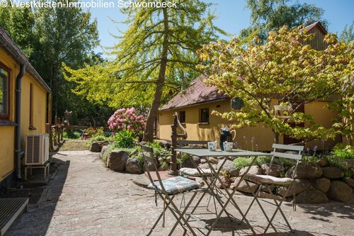 Terrasse mit schattenspendendem Baumbestand und naturnahem Freisitzbereich - 