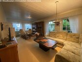 Helles Wohnzimmer mit großflächigen Fenstern und Gartenblick - 