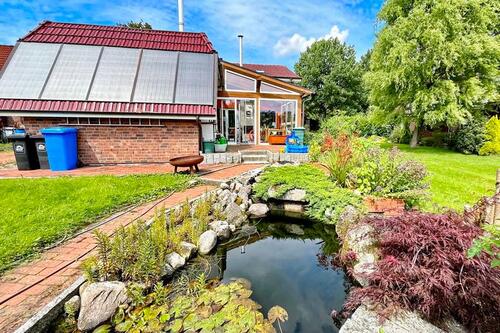 Blick vom Teich auf das Grundstück mit Wintergarten - 